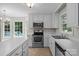 White kitchen with stainless steel appliances, island and a window with a view at 9904 Brigstock Ct, Charlotte, NC 28269