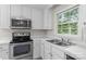 Bright kitchen featuring white cabinets, stainless steel appliances, and a double sink with a window view at 9904 Brigstock Ct, Charlotte, NC 28269