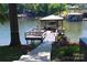 Lake view featuring a covered boat dock with seating area and steps from the landscaped lawn at 114 Caraway Ln, Mooresville, NC 28117