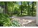 Landscaped backyard featuring lush greenery, a stone patio, and mature trees at 12524 Angel Oak Dr, Huntersville, NC 28078