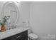 Bathroom features a dark vanity with marble countertop, oval mirror, and modern toilet at 12524 Angel Oak Dr, Huntersville, NC 28078