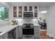 Renovated kitchen boasts stainless steel appliances, glass cabinetry, stone countertops, and view to the dining area at 12524 Angel Oak Dr, Huntersville, NC 28078