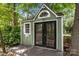Exterior shot of a green outbuilding with double glass doors, small window, and unique horseshoe detail at 12524 Angel Oak Dr, Huntersville, NC 28078