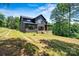 Expansive backyard view of a newly constructed two-story home with a dark exterior, a porch, and a sprawling green lawn at 130 Broken Arrow Dr, Statesville, NC 28677