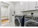 The laundry room is equipped with state-of-the-art, front-loading washer and dryer sets, sleek white cabinets, and utility sink at 130 Broken Arrow Dr, Statesville, NC 28677