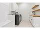 Modern laundry room features stylish tile floor, wooden shelves, and white cabinetry with a sink and black appliances at 130 Broken Arrow Dr, Statesville, NC 28677