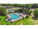 Aerial view of a community pool area with a lap pool, kiddie pool, slide, and tennis courts surrounded by lush trees at 17637 Snug Harbor Rd, Charlotte, NC 28278