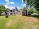 Backyard view showcasing a lush lawn, partial fence, and the building exterior under a partly cloudy sky at 1836 Fairlawn Ct, Rock Hill, SC 29732