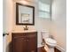 Bathroom features a wood vanity, a brown framed mirror, a white toilet, and hardwood floors at 18732 Coachmans Trce, Cornelius, NC 28031