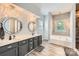 Bright bathroom features a double sink vanity, mirrors, modern light fixtures, and a large tub at 18732 Coachmans Trce, Cornelius, NC 28031