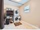 Bright laundry room with stacked washer and dryer, a window, and neutral-toned tile flooring at 18732 Coachmans Trce, Cornelius, NC 28031