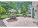 Stone patio with a table, chairs, and umbrella in a lush backyard setting at 18732 Coachmans Trce, Cornelius, NC 28031