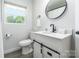 Bright bathroom with white vanity, black fixtures, round mirror, and natural light at 2116 Eastway Dr, Charlotte, NC 28205