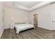Bright main bedroom with a king bed, neutral paint, tray ceiling, and bathroom access at 218 Tetcott St, Mooresville, NC 28115