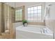 Bathroom with a soaking tub, a glass shower, a window and neutral tile and cabinets at 3831 Riceland Pl, Charlotte, NC 28216