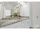 Bright bathroom featuring double sinks, granite countertops, white cabinets, and an accent flower display at 3831 Riceland Pl, Charlotte, NC 28216