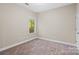 Empty bedroom with neutral carpet, cream walls, window with green outdoor view and white trim at 3831 Riceland Pl, Charlotte, NC 28216