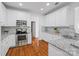 Well-lit kitchen boasts stainless appliances, granite countertops, white cabinetry and beautiful hardwood floors at 3831 Riceland Pl, Charlotte, NC 28216