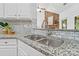 Close up of the kitchen sink with granite counters, white cabinets, stainless faucet, and a backsplash at 3831 Riceland Pl, Charlotte, NC 28216