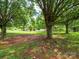 Expansive front yard with mature trees leading up to a charming home with a detached garage at 409 Ridge Rd, Clover, SC 29710
