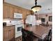 Cozy eat-in kitchen with wood cabinets, white appliances, and a decorative light fixture at 409 Ridge Rd, Clover, SC 29710