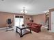 Spacious living room featuring a chandelier, brick red walls and carpet, with stairs in the background at 409 Ridge Rd, Clover, SC 29710