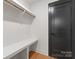Walk-in closet with built-in shelving and rod, complemented by a sleek black door and hardwood floors at 4117 Sarah Dr, Charlotte, NC 28217