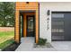 Stylish front entrance featuring wood accents, white brick, black trim, and a modern glass door at 4117 Sarah Dr, Charlotte, NC 28217