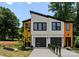 Modern duplex exterior features wood and white accents, black trim, and contemporary garage doors at 4117 Sarah Dr, Charlotte, NC 28217