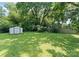 The backyard features a lush lawn, storage building and perimeter fencing at 5229 Tarrywood Ln, Charlotte, NC 28205