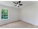 Bright bedroom features neutral carpet, a ceiling fan, and a large window overlooking the yard at 5229 Tarrywood Ln, Charlotte, NC 28205