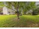 Expansive backyard featuring lush green grass, mature trees, and a charming deck for outdoor relaxation at 5707 Fairvista Dr, Charlotte, NC 28269