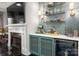 Stylish bar area with marble countertop, blue cabinetry, open shelving with lighting, and adjacent fireplace at 7221 High Point Ct, Charlotte, NC 28278