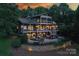 Expansive home featuring a multi-tiered deck and landscaped patio with fire pit and outdoor seating at dusk at 7221 High Point Ct, Charlotte, NC 28278