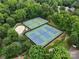 Aerial view showcases the community's well-maintained tennis courts, pool, and sand volleyball amid mature trees at 9137 Brightleaf Pl, Charlotte, NC 28269