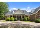 Beautiful stone house featuring a manicured lawn, dormer windows, and a charming front porch with stone columns at 9261 Marvin School Rd, Marvin, NC 28173