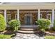 Inviting front porch with stone accents, decorative plants, ceiling fans, and a stylish front door with sidelights at 9261 Marvin School Rd, Marvin, NC 28173