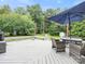 Outdoor deck with a seating area under a blue umbrella, surrounded by lush greenery at 1003 Snake River Ct, Monroe, NC 28110