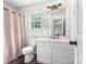 Cozy bathroom showcasing white vanity, toilet, mirror, and natural light from the window at 1003 Snake River Ct, Monroe, NC 28110