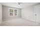 Bright bedroom featuring neutral carpet, a ceiling fan, and a window overlooking the yard at 1004 E Sandy Ridge Rd, Monroe, NC 28112