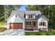 Charming two-story home with white siding, dark roof, inviting front porch, and a well-maintained, attached brown garage at 1004 E Sandy Ridge Rd, Monroe, NC 28112