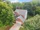 Aerial view of a brick home with a two-car garage, surrounded by lush greenery at 10919 Valley Spring Dr, Charlotte, NC 28277