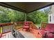 Covered outdoor deck with red furniture, a table, and a railing overlooking the yard at 10919 Valley Spring Dr, Charlotte, NC 28277