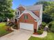 Aerial view of a brick home featuring a two-car garage, well-manicured lawn, and mature trees at 10919 Valley Spring Dr, Charlotte, NC 28277