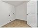 Empty laundry room with wood-style flooring and a white door, offering functionality and convenience at 113 Woodside Ave, Gastonia, NC 28054