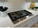 Close-up of a modern stainless steel gas cooktop on a clean, white countertop with subway tile backsplash at 11404 James Coy Rd, Davidson, NC 28036