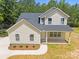 New construction home features a covered front porch, lush trees, and driveway at 130 Aurora Blvd, Matthews, NC 28105