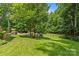 Large grassy backyard with seating areas, offering plenty of space and mature trees at 1310 Weddington Hills Dr, Matthews, NC 28104