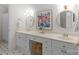 Bright bathroom with dual sinks, white cabinetry, granite counters, framed floral art, and tiled floor at 1310 Weddington Hills Dr, Matthews, NC 28104