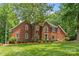 Charming red brick home with lush green lawn and mature trees offering curb appeal and natural beauty at 1310 Weddington Hills Dr, Matthews, NC 28104